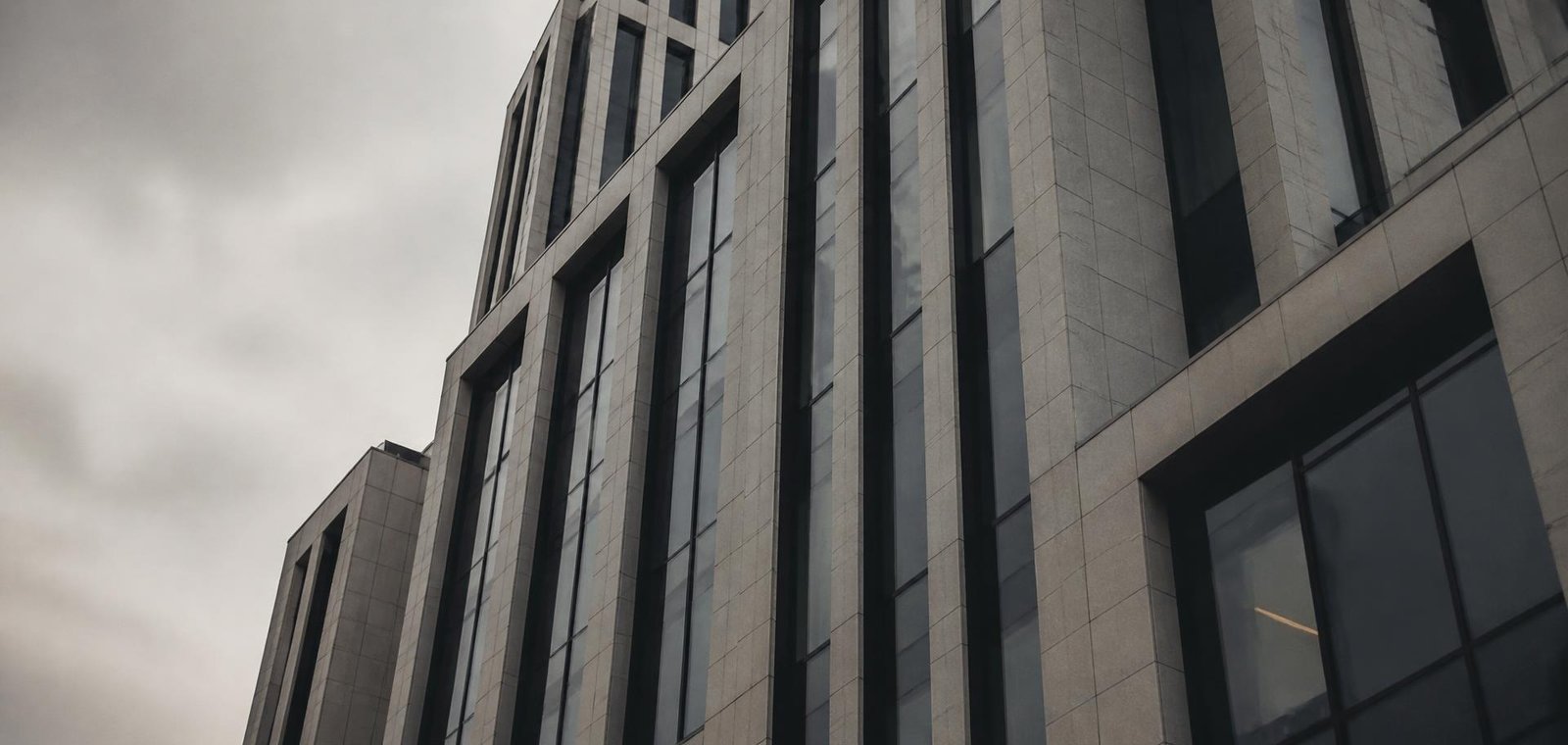 Stone and dark glass facade of a modern corporate building under overcast light